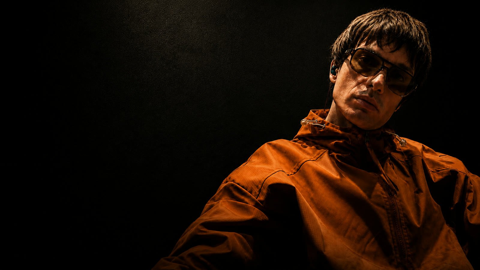 Liar Gallagher in an amber stage jacket and sunglasses