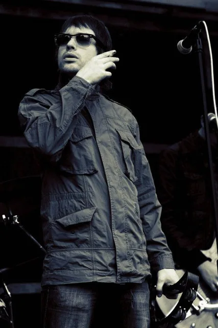 Liar Gallagher performing live in a parka with tambourine